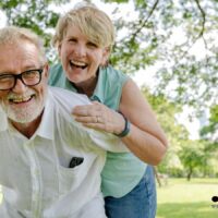 Älteres Paar lacht gemeinsam im Park; Symbolbild für abschlagsfreien Renteneintritt und sorgenfreien Ruhestand 2026 in Deutschland.